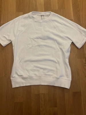 Vit t-shirt från H&M i bomull - Klassisk vit t-shirt från H&M i storlek S. T-shirten har rund halsringning, korta ärmar och är gjord i mjuk bomull. Perfekt basic-plagg att ha i garderoben och lätt att matcha med allt.