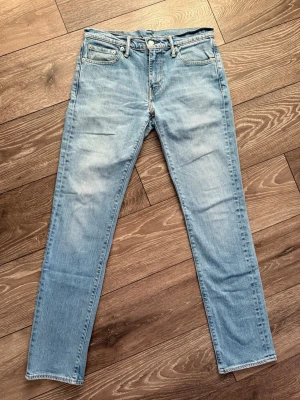 Levi's 511 ljusblå jeans W30 L32 - Säljer ett par Levi's 511 jeans i ljusblå tvätt. Klassisk femficksmodell med raka ben och normal passform. Jeansen har den ikoniska röda Levi's-lappen på bakfickan och patch i läder bak i midjan. Tillverkade i slitstarkt bomullsjeansmaterial.