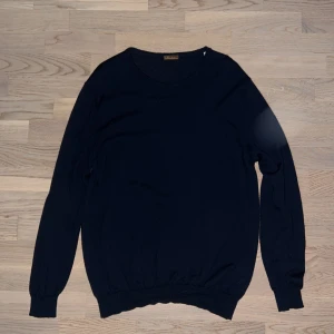 Mörkblå stickad tröja Stenströms - Snygg mörkblå stickad tröja från Stenströms med rund hals och långa ärmar. Tröjan har ribbade muddar vid ärmslut och nederkant, vilket ger en schysst passform. Perfekt för dig som gillar klassisk stil med en modern touch.