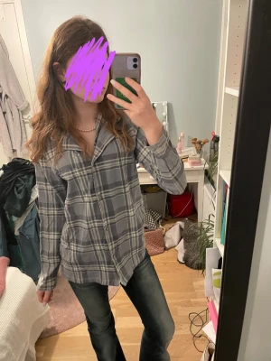 Grå rutig skjorta i bomull - Säljer en grå rutig skjorta med klassisk krage och knappar framtill. Skjortan har lång ärm och en loose passform, perfekt för en avslappnad stil. Tillverkad i mjuk bomull som känns skön mot huden.