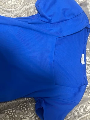 Kornblå topp från New Yorker - Säljer en kornblå topp från New Yorker med korta ärmar och rund halsringning. Toppen har en enkel och stilren design i ett mjukt, lätt material som känns skönt mot huden. Perfekt att matcha med jeans eller kjol för en snygg look.