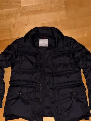 Svart Moncler pufferjacka med fickor - Säljer en svart pufferjacka från Moncler med flera fickor.