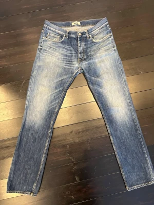 Blå jeans från Acne Studios - Säljer ett par klassiska blå jeans från Acne Studios med snyggt slitna detaljer och ljus tvätt. Dom är W34 L32.