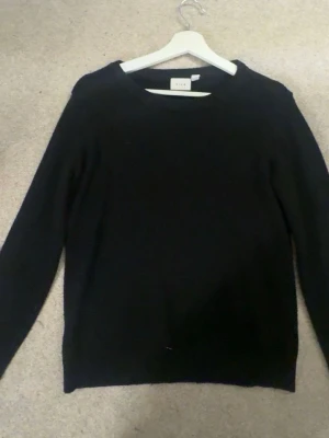Svart stickad tröja från Vila XS - Enkel och stilren svart stickad tröja från Vila i storlek XS. Tröjan har rund halsringning och långa ärmar, perfekt att matcha med jeans eller kjol för en clean look.