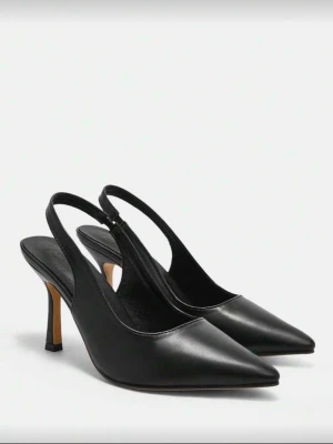 Svarta pumps med spetsig tå och klack - Säljer ett par stilrena svarta pumps med öppen häl och smal klack. Skorna har spetsig tå och är tillverkade i slätt skinnliknande material. Perfekta för dig som vill ha en klassisk och elegant look. Storlek 42. Passar även för lite bredare fötter. Säljer pågrund av att de är lite förstora för mig, är endast använda 1 gång.