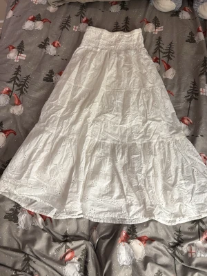 Vit långkjol med broderi från Gina Tricot - Säljer en vit långkjol från Gina Tricot i storlek 146/152. Kjolen har bred resår i midjan och är dekorerad med fina broderade blommor. Tillverkad i mjuk bomull, perfekt för sommarens alla dagar. Den har lite lite lite missfärgning vid kanten pågrund av solkräm.. Men det är ingeting man tänker på överhuvudtaget🩷