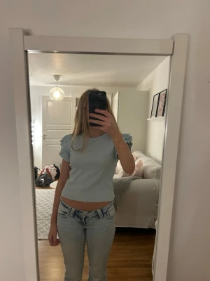 Ljusblå ribbad topp från Gina Tricot - Supersöt ljusblå topp från Gina Tricot som är ribbad med volangdetaljer på axlarna. Jag säljer toppen för att den nästan aldrig blivit använd, skriv gärna om ni har frågor och priset är alltid diskuterbart 💕toppen tvättas innan jag skickar iväg den 💕