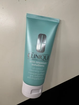 Clinique Anti-Blemish Solutions mask - En oljefri rengöringsmask från Clinique i en mintgrön tub med vitt lock. Masken är framtagen för att kontrollera olja och motverka blemmor. Tuben har silverfärgad logga och text i vitt. Perfekt för dig som vill ha en fräsch och klar hud.