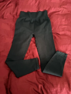 Svarta ribbade leggings från H&M Move - Svarta leggings från H&M Move i storlek S. De är ribbade och har en hög midja som sitter skönt och ger en snygg siluett. Perfekta för träning eller chill. Materialet är stretchigt och följsamt för maximal rörelsefrihet.