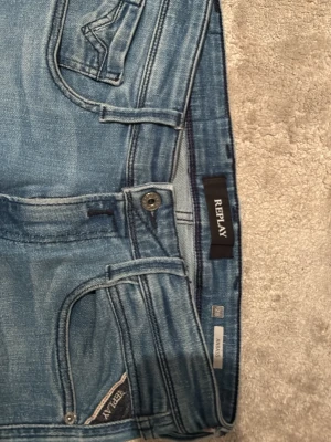 Replay Anbass blå jeans - Säljer ett par Replay Anbass jeans i klassisk blå tvätt. Jeansen har slim fit och raka ben, tillverkade i mjukt jeanstyg med dragkedja och knapp framtill. De är näst intill nya. Nypris ca 1200kr. Är mycket öppen för att gå ner i pris