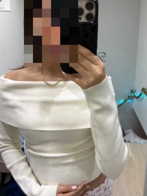 Vit offshoulder topp i ribbad bomull - Snygg vit offshoulder topp med lång ärm och bred kant över axlarna. Toppens ribbade material ger en skön och stretchig känsla. Perfekt för dig som gillar stilrena och trendiga plagg med en feminin touch. [ Gina tricot]