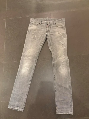 Ljusgrå  jeans från Dsquared2 - Säljer ett par ljusgrå jeans från Dsquared2 med slitna detaljer och klassisk femficksmodell. Jeansen har en snygg tvättad look, silverfärgad knapp och Dsquared2-logga vid fickan. Dom är äkta!! Bara att höra av sig om man har någon fråga. Pris kan diskuteras 