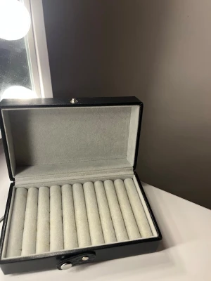 Elegant smyckesförsvaring  - Bilderna visar ett svart smyckeskrin med ljusgrå sammetsinredning för ringar