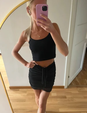 Svart kortkjol med snörning - Säljer denna svarta kortkjol med justerbar snörning framtill för en fin detalj. Kjolen har tyvärr aldrig kommit till användning av mig, så helt ny (endast testad). Ifrån NA-KD & i storlek XXS🖤