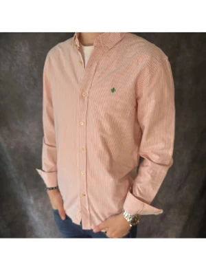 Rosa Skjorta Morris - Säljer en klassisk rosa och vit randig skjorta från Morris i mycket bra skick. Den har ett grönt broderat logomärke på bröstet. Skjortan har långa ärmar, normal passform och stängs med vita knappar framtill. Perfekt till jeans eller chinos för en clean look. Storlek M. 