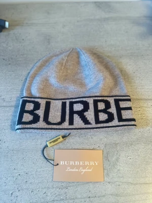 Burberry mössa - Helt oanvänd, snygg grå mössa från Burberry. Riktig ”snugg” och bekväm passform med tydlig designer-touch. Kommer med originaltagg och etikett. Kontakta gärna vid frågor:)😉