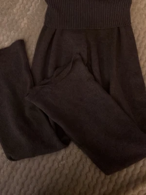 Mörkgråa, stickade utsvängda mjukisbyxor.💞strl: 146/152 - Mysiga mörkgråa stickade mjukisbyxor med bred ribbad midja. Byxorna har en loose passform och är perfekta för chill dagar hemma eller i skolan. Materialet är mjukt och ger en skön känsla mot huden. Snyggt minimalistiskt utseende utan synliga detaljer eller mönster.❤️