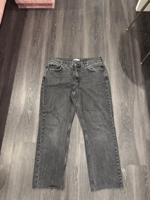 Svarta straight jeans från Gina Tricot - Svarta jeans från Gina Tricot i rak modell med klassisk femficksdesign. Jeansen har råa, avklippta benslut och en mörk tvättad finish. Tillverkade i jeansmaterial och passar dig som gillar en enkel och stilren look.
