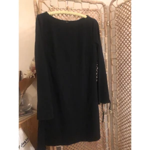 Svart långärmad klänning från Monki - En svart, enkel och stilren klänning från Monki i storlek 44. Klänningen har lång ärm med lätt utsvängd form och rund halsringning. Modellen är rak (lite lätt utsvängt nertill) och kort, perfekt för dig som gillar minimalistisk stil.