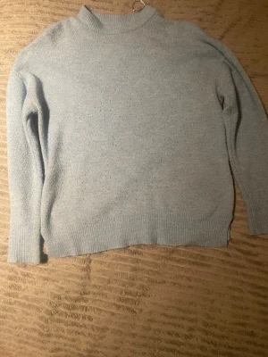 Ljusblå stickad tröja med ribbad kant - Mysig ljusblå stickad tröja med ribbad kant vid hals, ärmslut och nederkant. Är lite mer starkare blå i verkligheten.