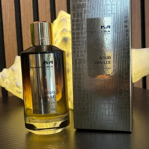 Mancera Aoud Vanille EdP 120ml - Lyxig parfym från Mancera, Aoud Vanille, i en elegant glasflaska med guldigt lock och metallisk etikett. Flaskan har en snygg gradient från svart till bärnstensfärgat glas. Doften är en mix av oud och vanilj, perfekt för dig som gillar unika och varma parfymer. Cirka 107/120 Ml kvar köpt för 1300 säljer för 870