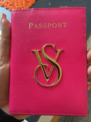 Rosa passfodral från Victoria's Secret - Snyggt och praktiskt passfodral i starkt rosa skinn från Victoria's Secret. Utsidan har ett stort guldfärgat VS-emblem och insidan har flera kortfack. Perfekt för att hålla pass och kort samlade på resan. Denna finns ej kvar idag att köpa vilket gör den väldigt unik. 