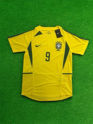 Brasilien Ronaldo 9 Nike matchtröja - Gul Brasilien matchtröja från Nike med gröna detaljer, nummer 9 och Ronaldo på ryggen. Klassisk design med landslagets emblem och Nike-logga på bröstet. Perfekt för dig som älskar fotboll och vill hylla en ikon.