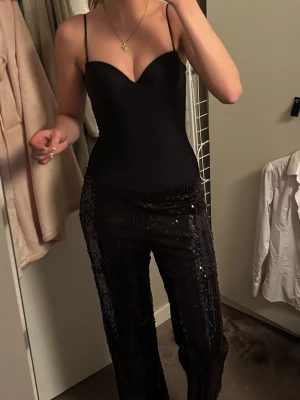 Svarta paljettbyxor - Säljar dessa ascoola svarta glitter/paljett byxorna i storlek S, endast andvända en gång och är helt perfekta att ha på nyår med en snygg topp. Skulle säga att de är midrise men även assnygga att ha som lowrise om man drar ner de lite. Långa i benen på mig som är 176 cm lång. Köpa på Lindex för 599 kr!💕