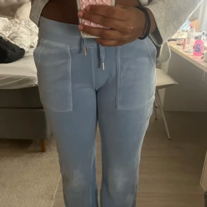 Blå mjukisbyxor Juicy Couture XS - Säljer ett par ljusblå mjukisbyxor från Juicy Couture i storlek XS. Byxorna har dragsko i midjan, stora fickor fram och bakfickor med knappar. Mjukt och skönt material, perfekta för chill dagar.