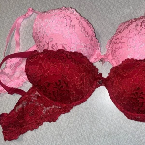 2 push-up bh:ar rosa & röd i storlek 65C - Säljer två snygga push-up bh:ar i storlek 65C, en i ljusrosa och en i vinröd. Båda har vacker spets med blommigt mönster och tunna axelband. Liten rosett i mitten på båda två. Skulle säga att dom är nästan nyskick då dom är extremt sparsamt använda. Från Cubus 