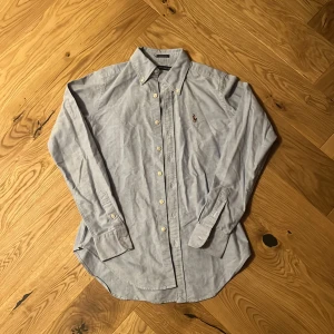Ralph Lauren skjorta - Blå Ralph Lauren skjorta. Riktigt snygg skjorta som sitter mer slim. ”Skinny fit” sjukt nice passform och färg. Passar dig som är ca 164-172. Den har en fläck på baksidan. Har inte testat att tvätta bort men det går säkert. Nypris ca 1400 mitt pris: 350kr. Mycket bra skick