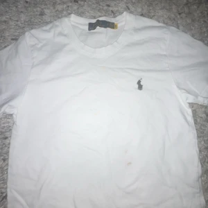 Vit t-shirt från Polo Ralph Lauren - Vit klassisk t-shirt från Polo Ralph Lauren med rund halsringning och ikonisk broderad logga på bröstet. Tillverkad i mjuk bomull och har en enkel, stilren design som passar till allt. Perfekt basplagg för garderoben.