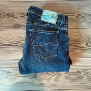  Jacob Cohen jeans  688 - Säljer ett par blå jeans från Jacob Cohen i storlek 34. Jeansen har klassisk femficksdesign, snygga kontrastsömmar och en vit patch med blå logga bak. Materialet är mjukt denim. 