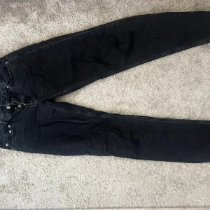 Svarta jeans från 157 med raka ben - Svarta jeans från 157 med raka ben och klassisk femficksdesign. Jeansen har knäppning med flera silverfärgade knappar och bakfickor med lock och knapp. Materialet är robust denim i bomull och passformen är normal.
