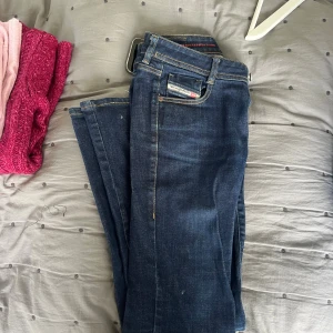 Mörkblå Diesel jeans straight fit - Snygga mörkblå jeans från Diesel med klassisk femficksdesign och raka ben. Jeansen har diskreta kontrastsömmar och en liten logotypdetalj på fickan. Perfekta för dig som gillar en tidlös och stilren look.