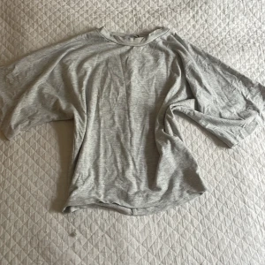 Ljusgrå t-shirt från 157 i XS - Ljusgrå t-shirt från 157 i storlek XS. Modellen är klassisk med rund hals och korta ärmar. Materialet känns mjukt och lätt, perfekt för en chill och enkel stil. Passformen är normal och färgen är diskret grå, vilket gör den enkel att matcha med allt.