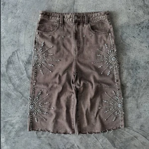 Brun denimkjol med pärlbroderi - Cool brun jorts i denim från Tenth Series med råa kanter och detaljerade pärlbroderier i stjärnform på sidorna. Perfekt för dig som vill sticka ut med unika detaljer.