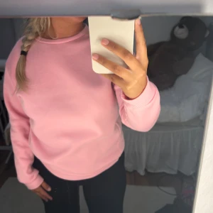 Ljusrosa sweatshirt i bomull - Enkel och snygg ljusrosa sweatshirt med rund hals och långa ärmar. Tröjan är i mjuk bomull och har ribbade muddar vid ärmslut och nederkant. Perfekt för en chill och avslappnad stil.