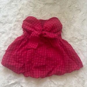 Rutig rosa bandeau tubtopp med rosett - Säljer en superfin rutig rosa bandeau tubtopp med stor rosett framtill. 