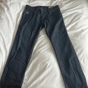 Mörkblå Diesel jeans - Säljer ett par mörkblå jeans från Diesel, modell Darron. Klassisk femficksdesign med snygga kontrastsömmar och raka ben. Jeansen är tillverkade i slitstarkt denim och har en stilren look som passar till det mesta. W32 L32