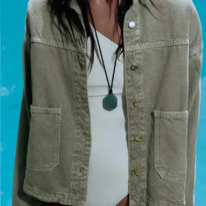 Grön jeansjacka med stora fickor - Snygg beige jeansjacka med stora framfickor och knappar framtill. Jackan har en rak passform och klassisk krage, perfekt att slänga över en t-shirt eller hoodie. Materialet är robust denim som ger en cool och avslappnad vibe.