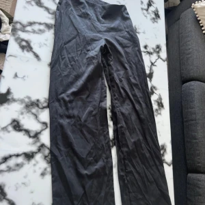 Svarta vida byxor i bomull - Säljer ett par svarta byxor med vid passform och hög midja. Byxorna är tillverkade i ett mjukt bomullstyg och har en stilren look som passar till många olika outfits. Perfekta för dig som gillar en avslappnad men trendig stil.