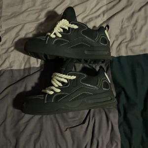 Chunky svarta sneakers från Zara - Chunky svarta sneakers från Zara med kraftig vit snörning och kontrasterande vita detaljer. Skorna har en tjock platt sula, rund tå och markerade sömmar som ger en cool streetstyle-vibe. Materialet är syntet och textil, perfekt för dig som gillar statement-sneakers.