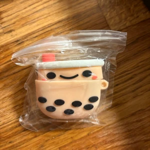 AirPods-fodral Boba Tea - Sött AirPods-fodral i form av en boba tea med leende ansikte. Tillverkad i mjuk silikon, skyddar dina AirPods mot repor och stötar. Produkten är oanvänd och levereras i originalförpackning. Passar perfekt för dig som vill ha ett unikt och roligt tillbehör.