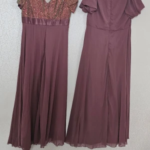 Långlänning i lila med paljettdetaljer - Två eleganta långklänningar i lila nyans. Ena klänningen har glittrig paljettöverdel och v-ringning, medan den andra har draperad överdel och korta ärmar. Båda har flytande kjol i lätt tyg och markerad midja. Perfekt för speciella tillfällen.