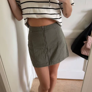 Grön kjol - Säljer en olivgrön kortkjol från H&M Divided, storlek 34