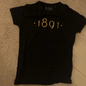 Aik tröja 1891 - Aik tröja med guldig 1891 text. Aldrig använd och den har ”prislappen” kvar som man ser på andra bilden. Barnstorlek i 8-10 men den passar mig som har xs ibland S i storlek och den sitter inte för tajt i armarna, kragen eller i midjan. Tveka inte vid frågor eller vid frågor om flera bilder på hur den ser ut på osv