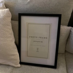 Photo Frame 30x40cm - Elegant svart fotoram i storlek 30x40 cm, perfekt för att visa dina favoritbilder. Ramen är i mycket gott skick utan synliga repor eller skador. Kan hängas både vertikalt och horisontellt tack vare flexibla fästen på baksidan.