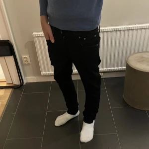 Svarta Nudie Jeans Lean Dean 30/30 - Svarta jeans från Nudie Jeans, modell Lean Dean. Snyggt minimalistisk look med klassisk bakficka och diskret logga. Tillverkade i 99% bomull och 1% elastan för en bekväm passform. Perfekta för dig som gillar stilrena och smala jeans.