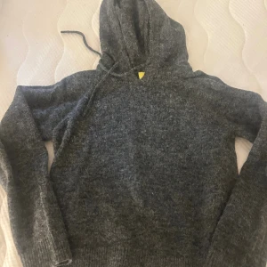 Grå stickad hoodie från JJXX XS - Mysig grå stickad hoodie från JJXX i storlek XS. Tröjan har huva med snörning och långa ärmar. Perfekt för kyliga dagar när du vill vara både bekväm och snygg.
